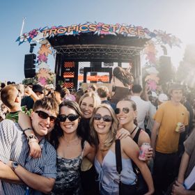 A group of young happy people outside at a music festival on a sunny day