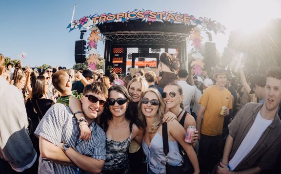 A group of young happy people outside at a music festival on a sunny day