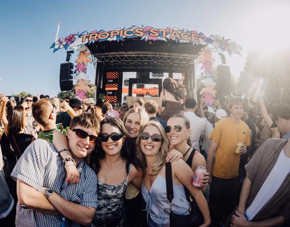 A group of young happy people outside at a music festival on a sunny day