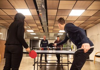 Four people from DataTorque playing table tennis inside an office building.