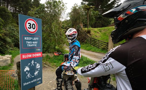 Two motorbike riders looking at 30km speed limit sign on the Karapoti Classic Course.