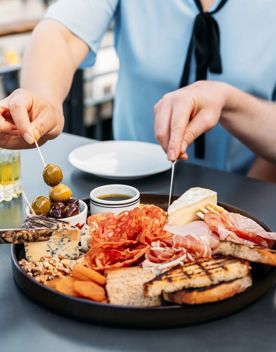 Three people grabbing food from a charcuterie board at Foxglove on Queens Wharf.
