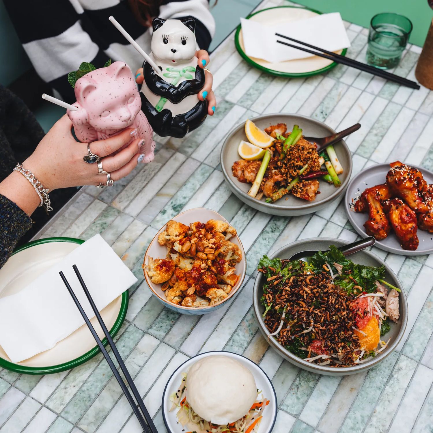 Shared Asian-style dishes and drinks served on a marble table.