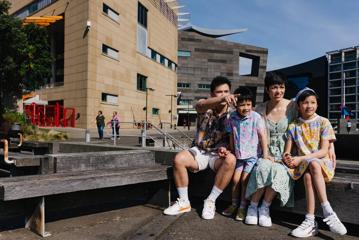 A family of four sit on a bench outside of Te Papa.