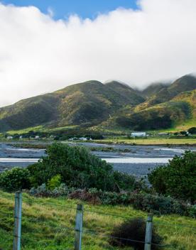 The screen location of Ōrongorongo Station, with many buildings, old and new, as well as views of the ocean and mountains.