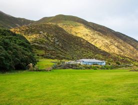 The screen location of Ōrongorongo Station, with many buildings, old and new, as well as views of the ocean and mountains.