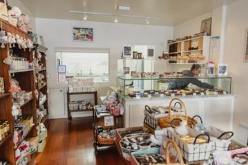 The interiror of The Chocolate Story Petone, where a worker is laying out chocolate behind the counter.