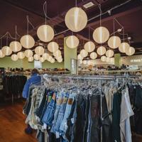 The inside of Recycle Boutique on Vivian Street, circle lantern lights hang from the ceiling and racks of clothes around the room. A rack of denim jeans is in the forefront.