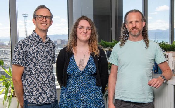 Brian Johnston, Luna Wilkes, and Mog Nesbitt stand next to each other at the Cogo office.