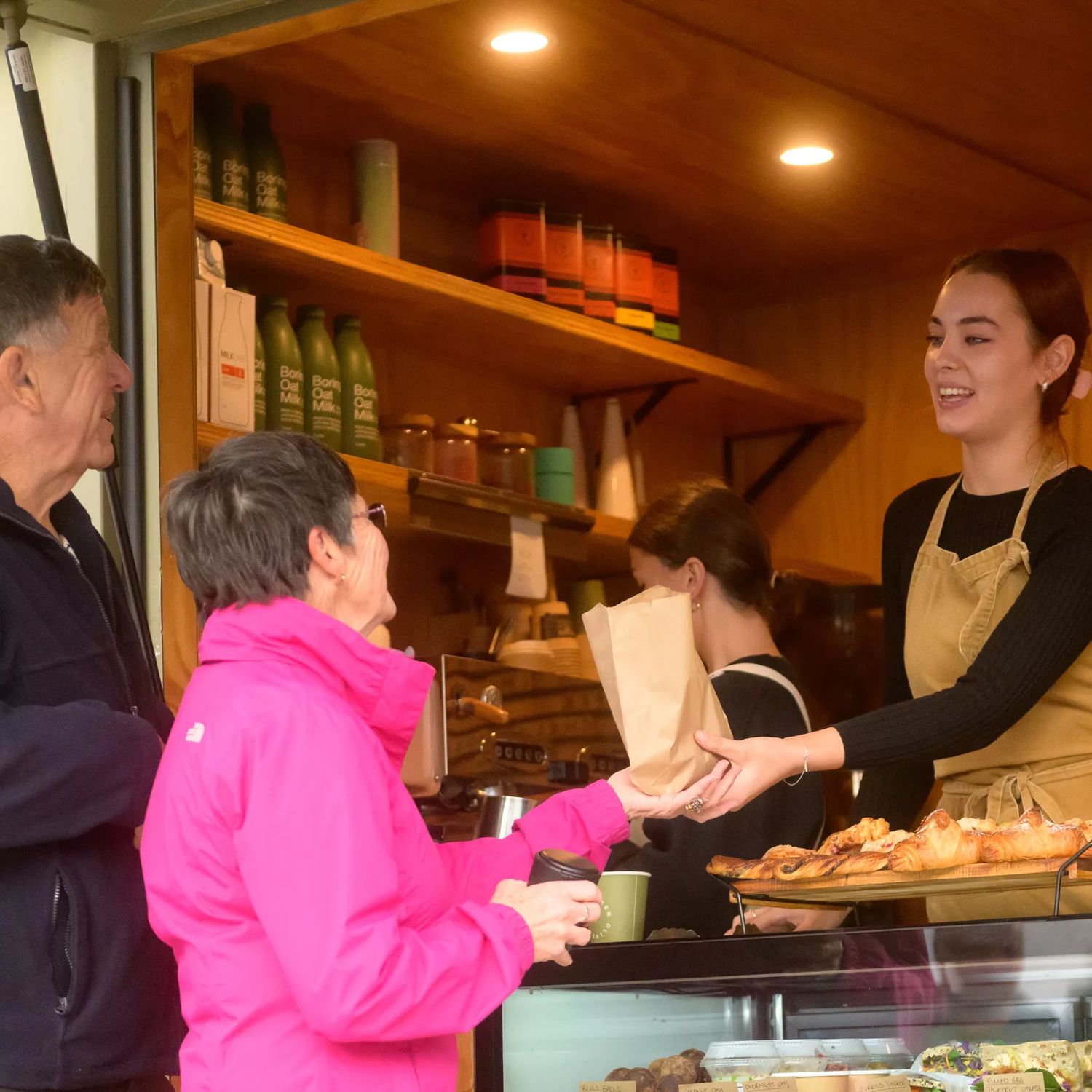 A barista hands a brown paper bag with food in it to a customer at Little Green Olive in Porirua.