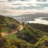 A scenic view of Porirua Harbour from  Colonial Knob Walkway on Mount Rangituhi. A cyclist is riding their mountain bike on the trail.