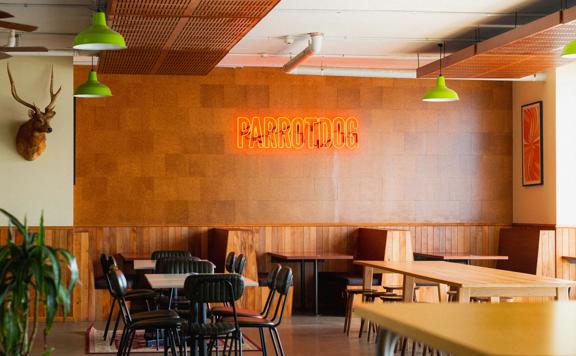 Inside Parrotdog Bar & Brewery there are tables, chairs, wood-panelling, a taxidermied deer head and a neon sign on the wall. 