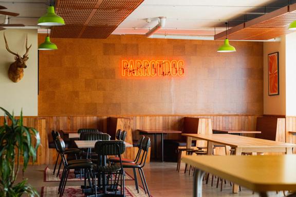 Inside Parrotdog Bar & Brewery there are tables, chairs, wood-panelling, a taxidermied deer head and a neon sign on the wall. 