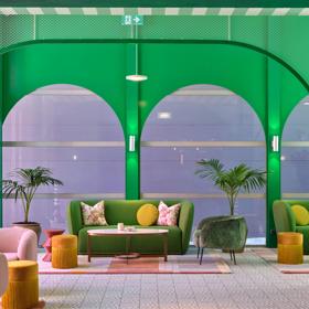 the funky green lobby inside Naumi Hotel, green walls, couch and roof surround the room, with pops of pink and yellow.