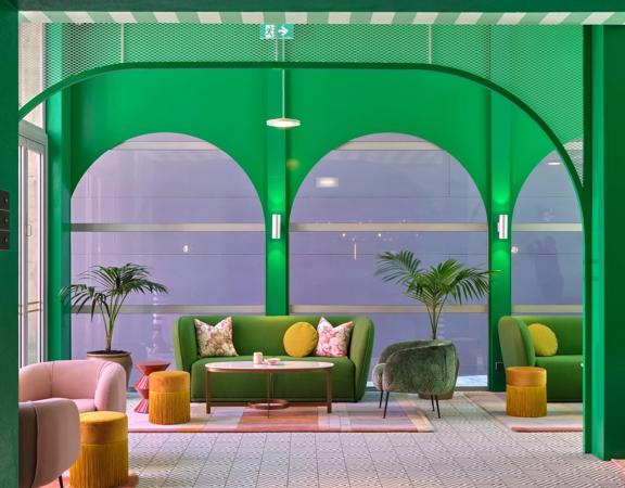 the funky green lobby inside Naumi Hotel, green walls, couch and roof surround the room, with pops of pink and yellow.