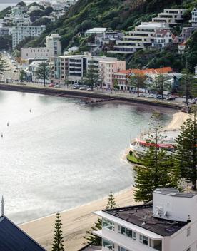 The screen location of Oriental Bay, wth pastel-coloured, Art Deco apartments, brightly-painted boat sheds, and the golden beach.