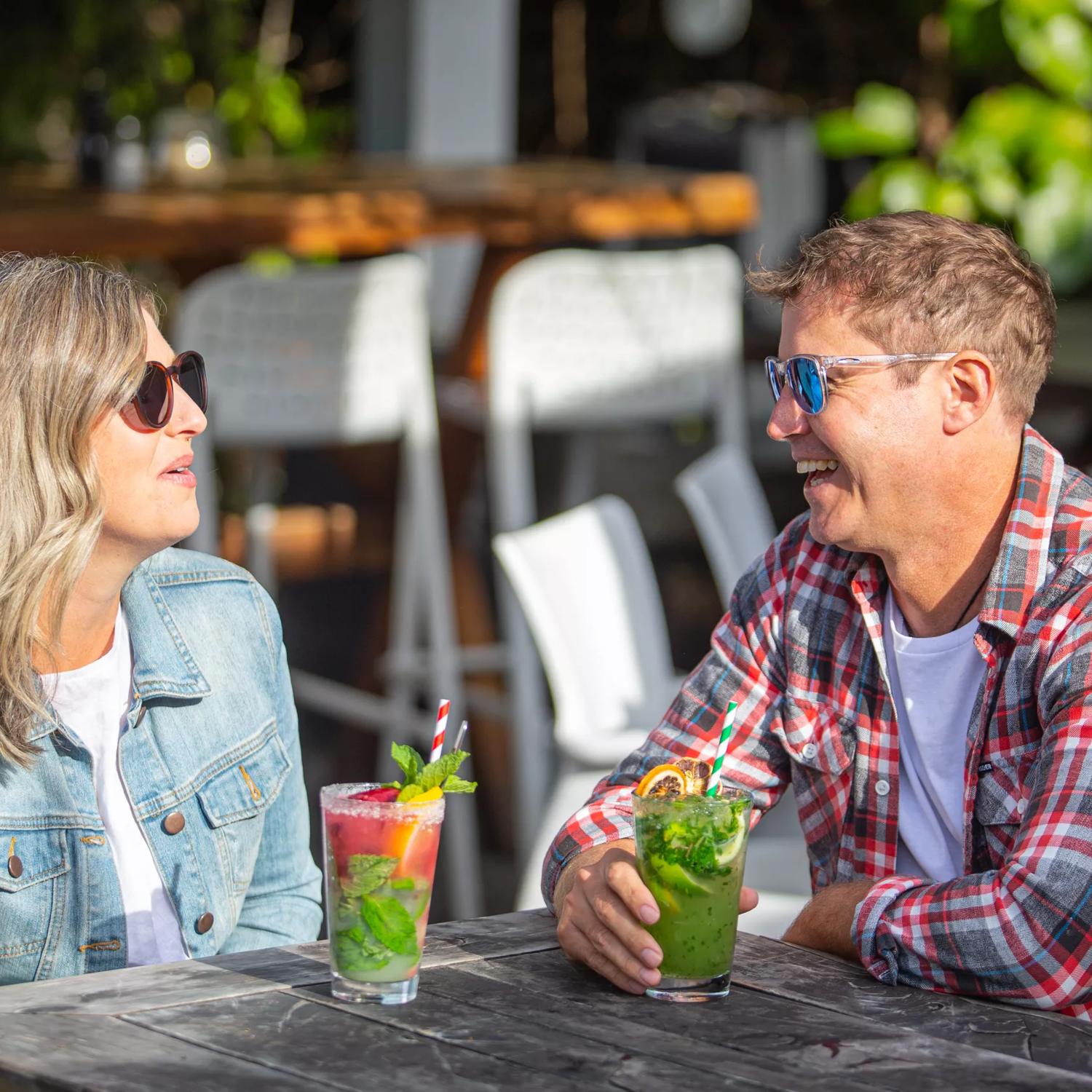 2 people enjoying cocktails in the sun outside Long Beach.