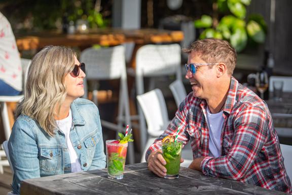 2 people enjoying cocktails in the sun outside Long Beach.