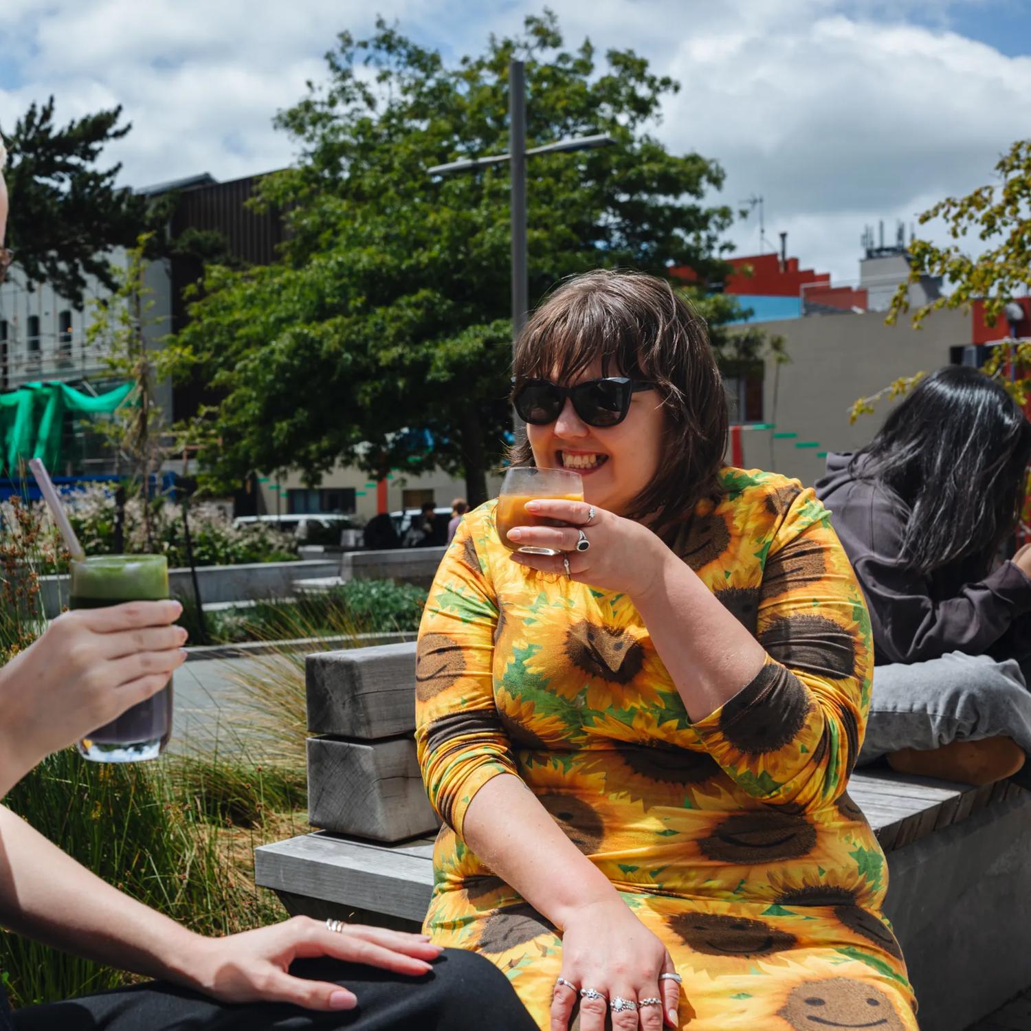 Two friends enjoy iced coffees at Glover Park in Te Aro, Wellington.