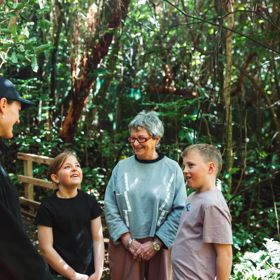 Two kids and an adult are on a guided walking tour at Zealandia.