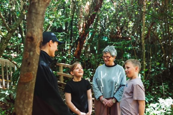 Two kids and an adult are on a guided walking tour at Zealandia.