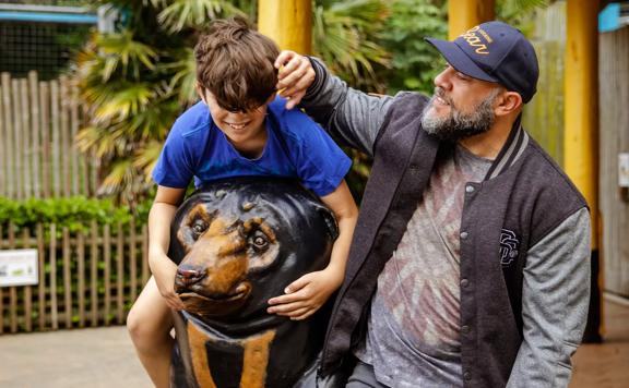 Wellingtonian Allan Henry, who plays the bear in ‘Cocaine Bear’, with his child at the Wellington Zoo, climbing on top of a statue of Sasa the Sun Bear.