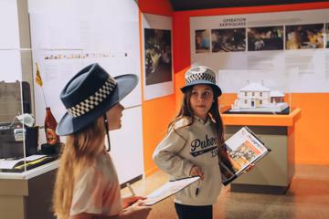 Two young children do a fact-finding activity using clipboards and pens at the New Zealand Police Museum.