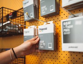 A hand reaching for a pack of Polaroid film.