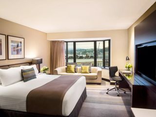 A room at the InterContinental Wellington showing a bed, couch desk and Wellington city in the background