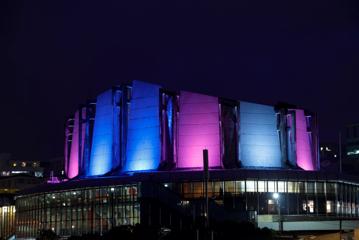 The Michael Fowler Centre, a performance venue, lit up with blue and purple lights at night.