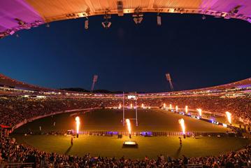 Interior view of the stadium in Wellington showing orange and pink lighting, and large flame displays on the pitch.