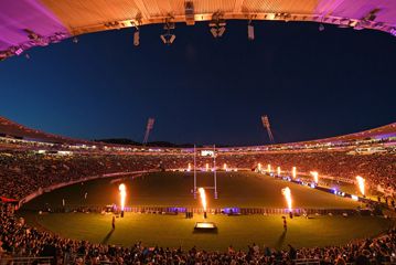Interior view of the stadium in Wellington showing orange and pink lighting, and large flame displays on the pitch.
