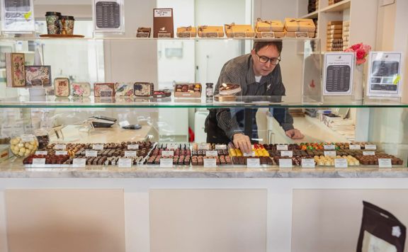 A staff member arranging chocolates in the glass cabinet inside The Chocolate Story/