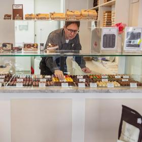 A staff member arranging chocolates in the glass cabinet inside The Chocolate Story/