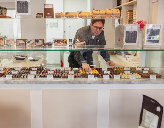 A staff member arranging chocolates in the glass cabinet inside The Chocolate Story/