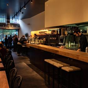 The dim and moody interior of Highwater eatery with customers siitng and bar staff working.