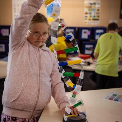 A young child plays with a colourful model of DNA sequence.