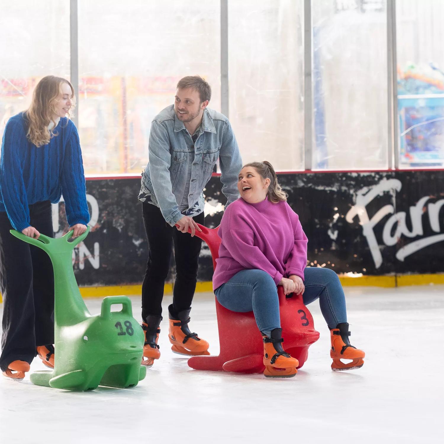 A group of people ice skating at Daytona Adventure Park in Upper Hutt, supporting themselves with two dolphin skate assists.