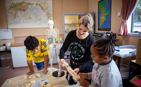 2 Young children and an adult inspect mini plastic skeletons at house of Science.