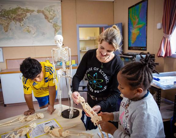 2 Young children and an adult inspect mini plastic skeletons at house of Science.