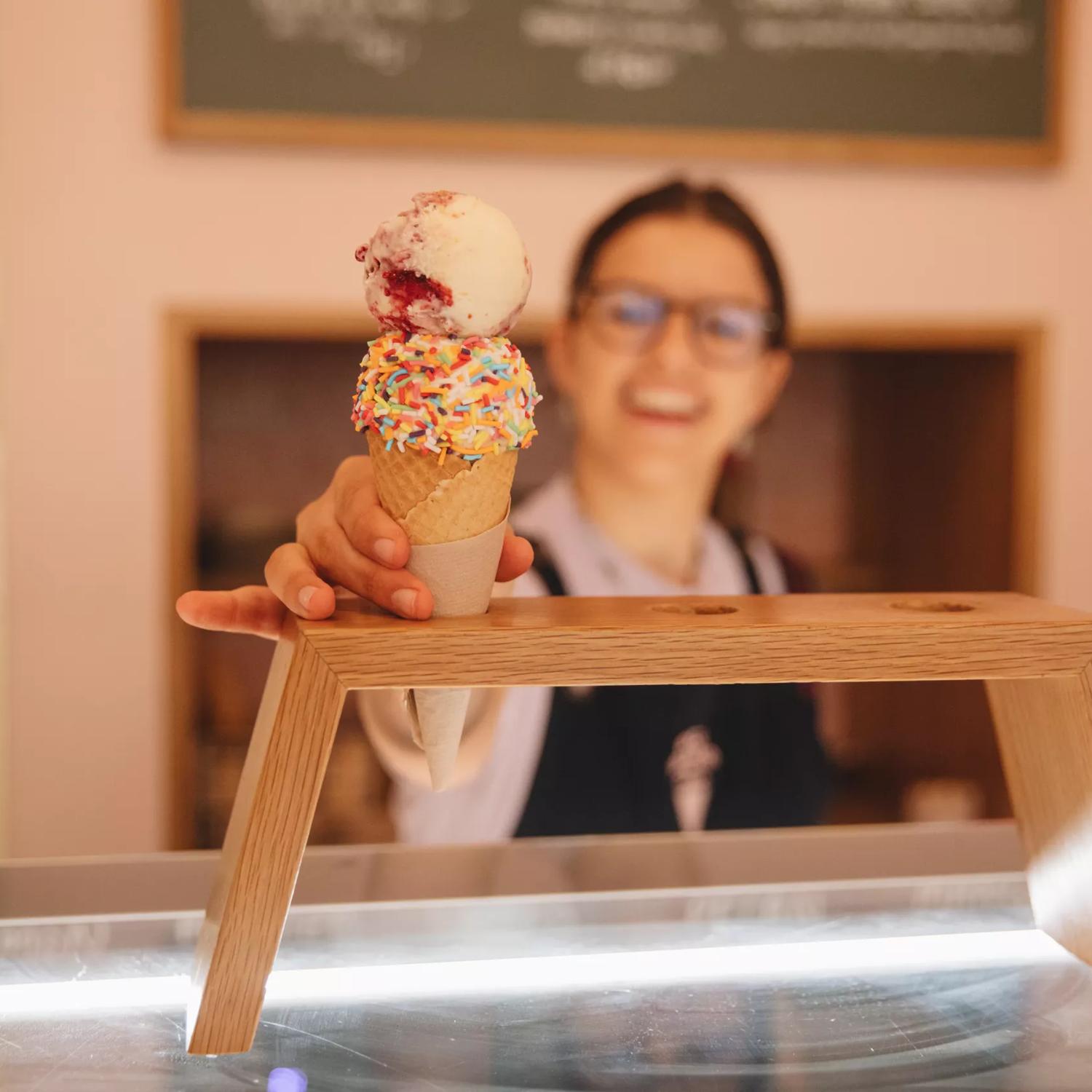 A staff member handing over an ice cream with sprinkles from Duck Island, Cuba Street.