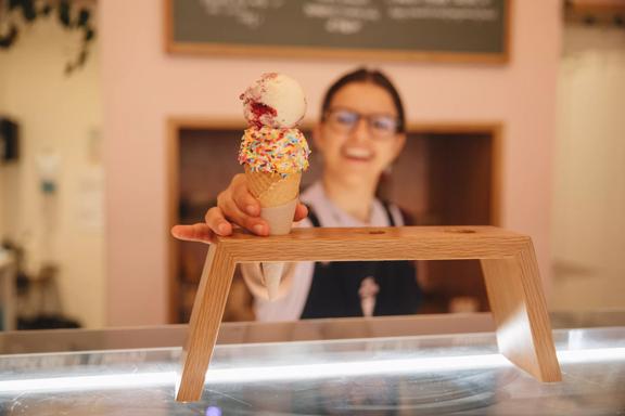 A staff member handing over an ice cream with sprinkles from Duck Island, Cuba Street.