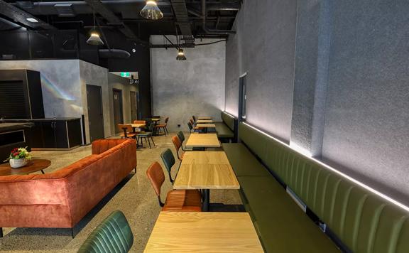The café at Microtel by Wyndham Wellington, a four-star hotel located on Vivian Street in Te Aro, Wellington. The walls are grey, the seating is dark green and orange and tables are light-coloured wood. 