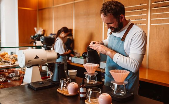 A couple of baristas prepare coffees.