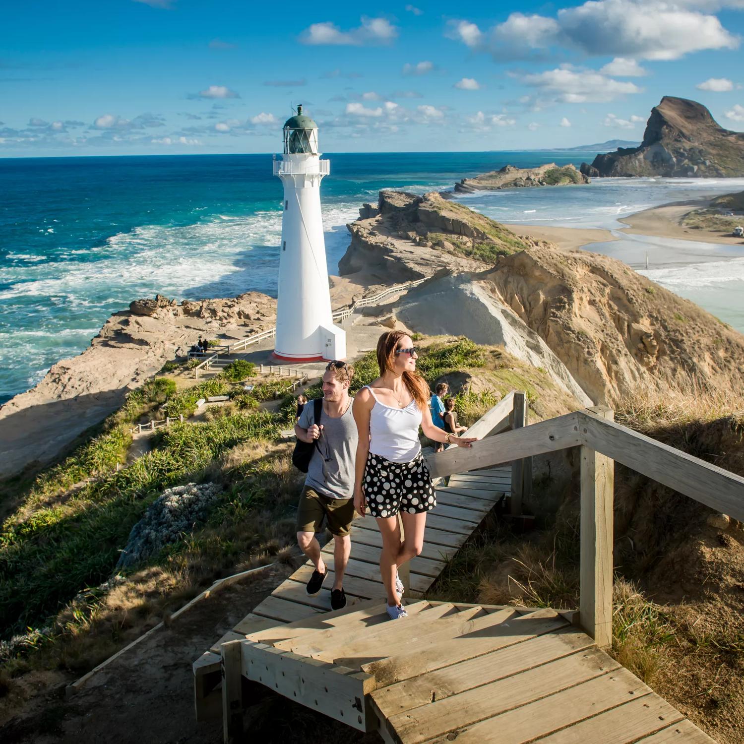 Castlepoint, Wairarapa. Two people are walking up the steps in front of the Castlepoint Lighthouse.