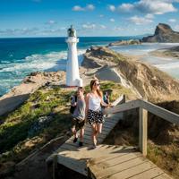 Two people are walking up the steps in front of the Castlepoint Lighthouse in the Wairarapa region.