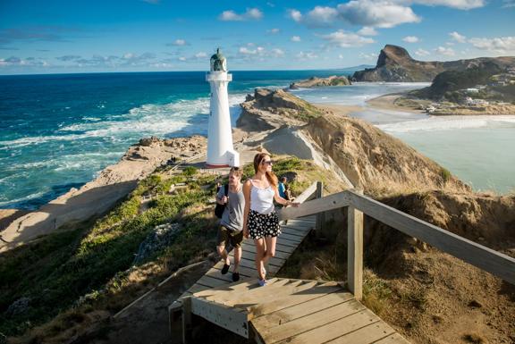 Two people are walking up the steps in front of the Castlepoint Lighthouse in the Wairarapa region.