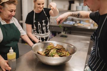 3 chefs preparing food in the kitchen of Everybody eats.