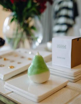 A porcelain figurine of a pear on display with some accessories.