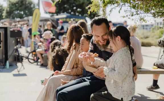 A family sitting and enjoying food from the Harbourside markets.